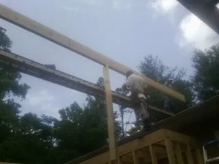 Carpenter setting a ridge beam over a new addition frame — Ice Dam Removal by Roofing Brothers in Pursglove