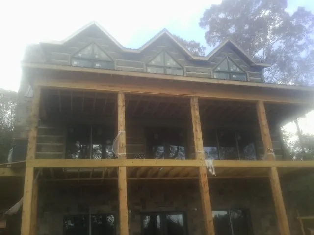 Dormers and porch framing on a large log home under construction — Roof Coating work by our crew in Pursglove