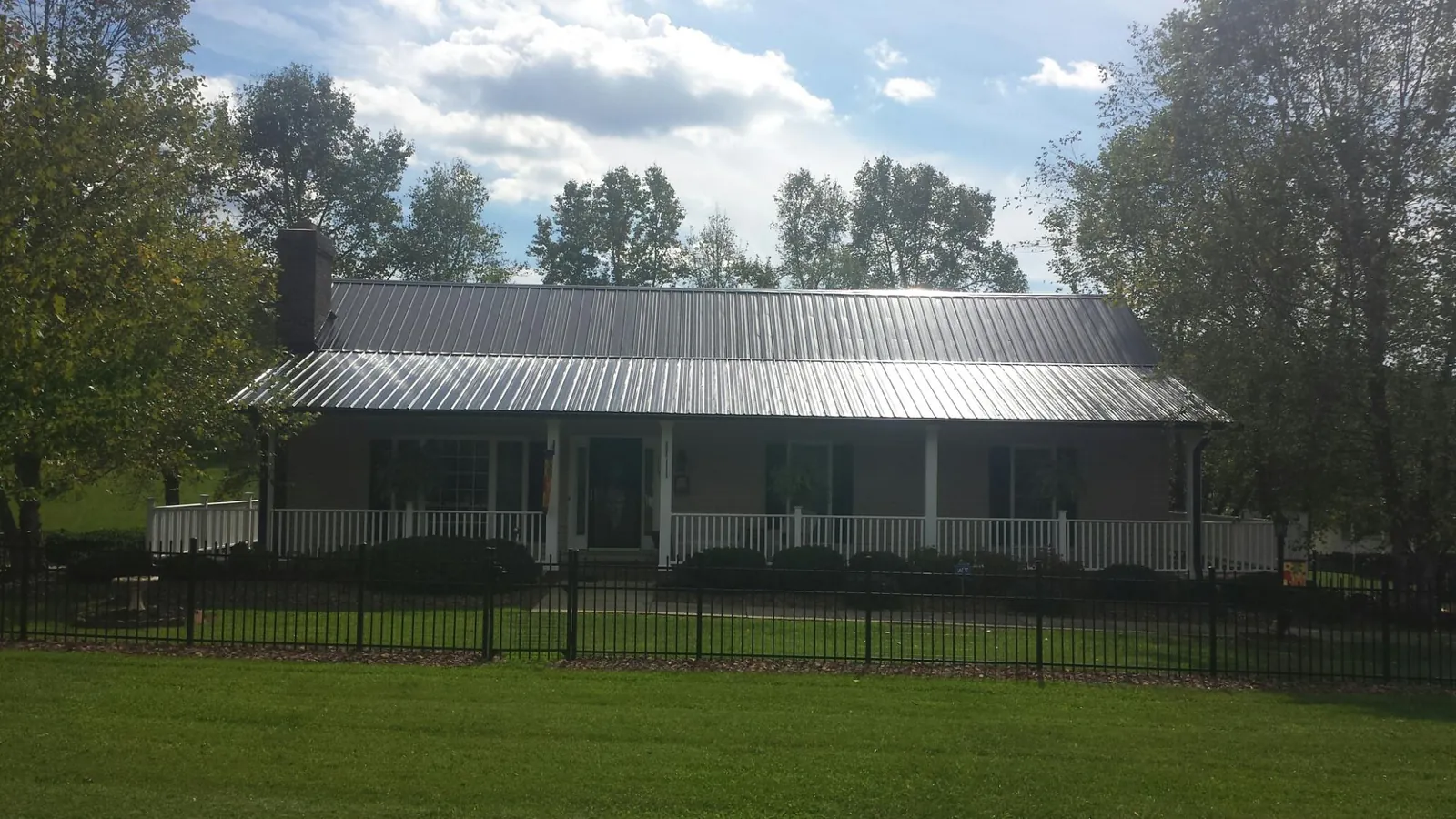 Gray metal roof on a brick ranch with a full width front porch — Gutter Guard Installation work by our crew in Pursglove