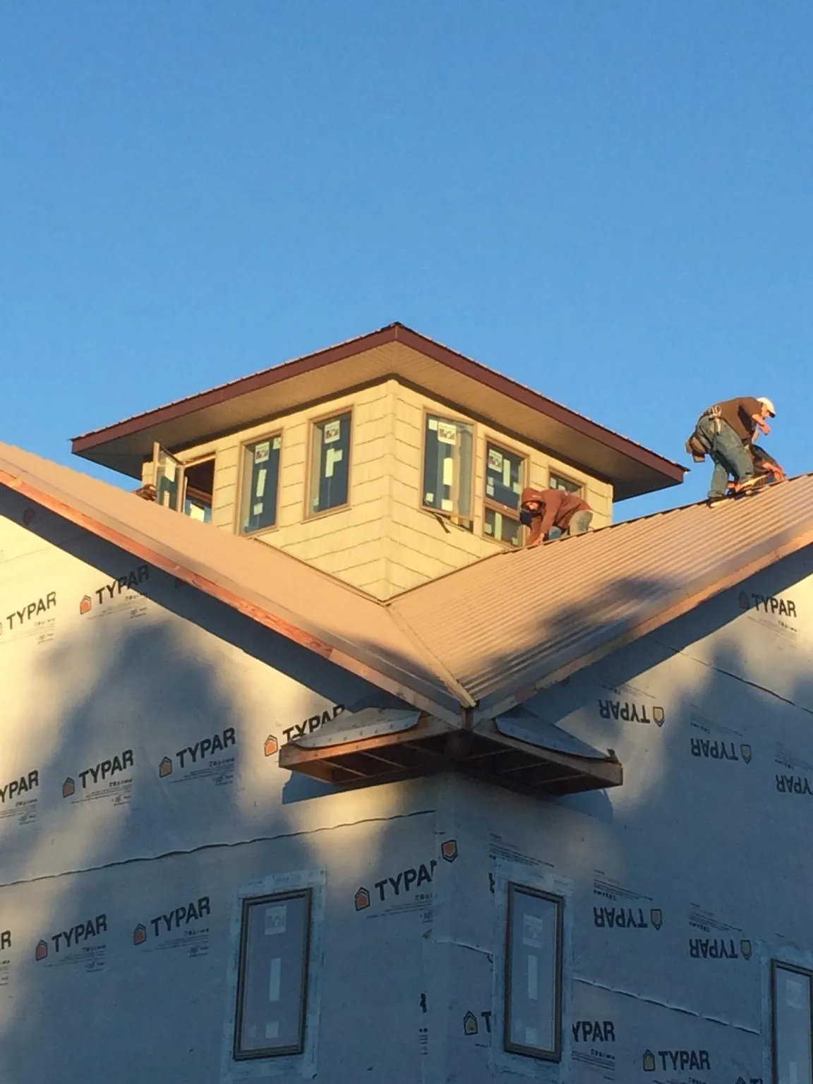 Roofers working around a rooftop cupola on a new metal roof at sunset — Roof Waterproofing in Pursglove by Roofing Brothers